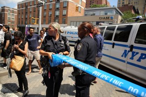 Police officers put up police tape near where two U.S. Marshals and one New York Police Department detective were shot in the afternoon along a quiet street on July 28, 2014, in the West Village of Manhattan, New York City. (Credit: Spencer Platt/Getty Images)