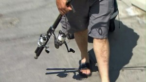 A man carries fishing poles near the Manhattan Beach pier. (Credit: KTLA)