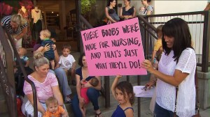 A girl holds up a sign in support of breast feeding outside the Beverly Hills Anthropologie store on Wednesday, Aug. 20, 2014. (Credit: KTLA)