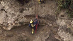 A rescuer helps a man up the side of a cliff at Point Fermin on Friday morning. (Credit: KTLA) 