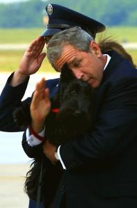 President George W. Bush tries to salute the security officers at the steps of Air Force One as he holds his dog Barney, after returning from a speech to the U.S. Conference of Mayors in Detroit. (Credit: Paul J. Richards/AFP/Getty Images)