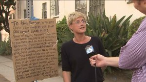 Annie Preece of Beverly Grove stands next to a sign on Tuesday, Sept. 9, 2014, warning dog owners to pick up after their pets. (Credit: KTLA)