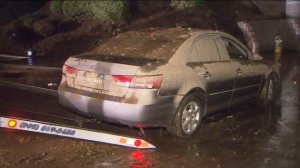A mud-caked car was towed after being trapped in floodwater on Sept. 8, 2014. (Credit: KTLA)