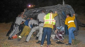 CHP officers, LAPD officers and paramedics held up a vehicle to rescue a trapped driver who was screaming for help after a rollover crash on Sept. 16, 2014. (Credit: Rick McClure, RMc Video) 