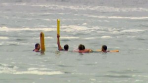 Four lifeguards signal a boat as they wait with a distressed swimmer at the Wedge in Newport Beach on Friday, Sept. 5, 2014. (Credit: KTLA)