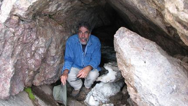 Mike O’Hanlon crouches at the entrance to the Spanish Caves. (Credit: University of Northern Iowa)