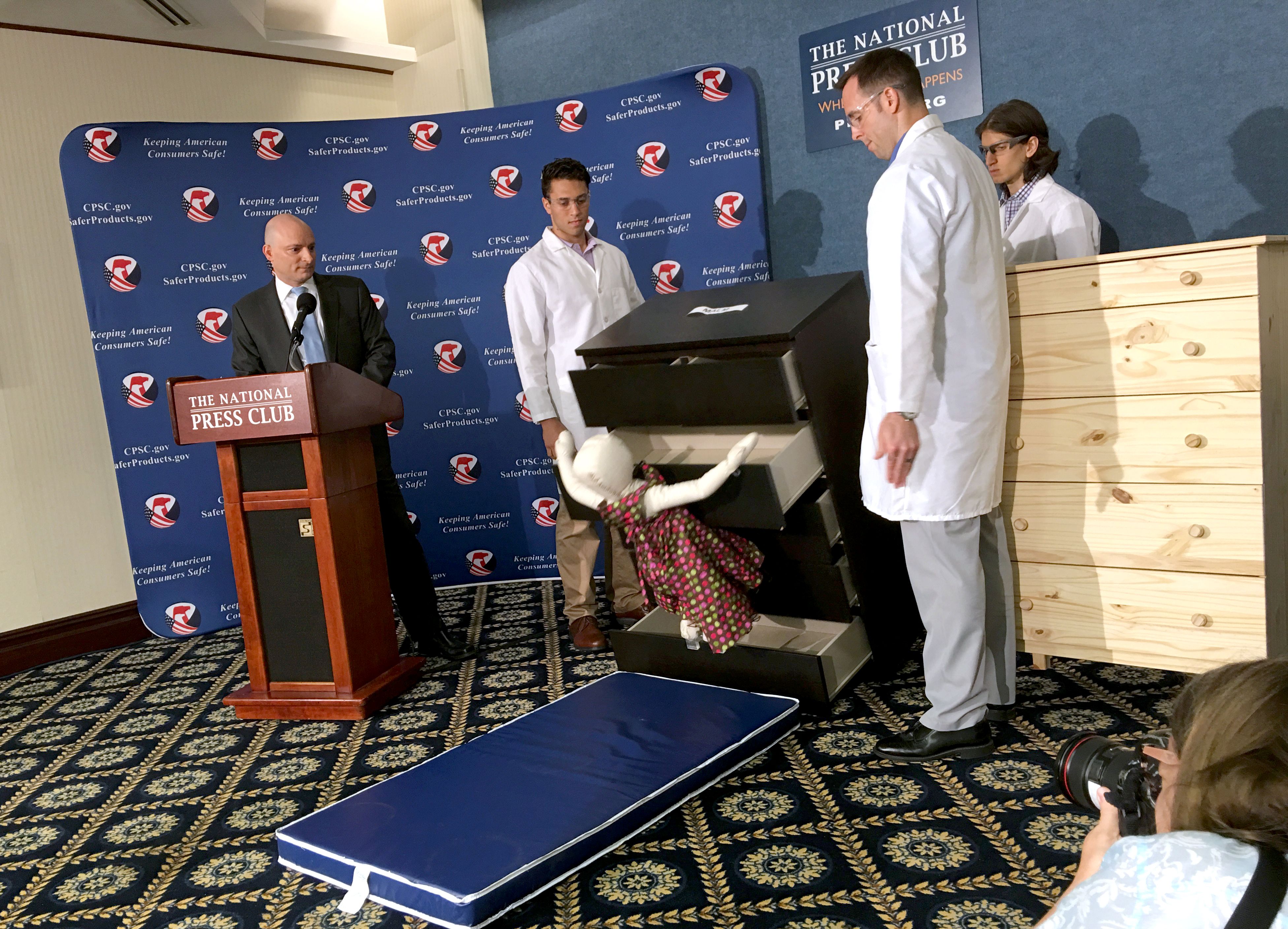 Elliot Kaye (L), chair of the Consumer Product Safety Commission (CPSC) and CPSC employees watch as a 28-pound (13 kilo) dummy(C) falls over and under IKEAs Malm model chest of drawers, during a live demonstration at the National Press Club in Washington, DC 28 June, 2016. (AFP / Carlos Hamann)
