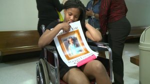 A 12-year-old girl holds a picture of another girl who was brain dead after the two them were hit by a car.