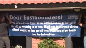 Crew hangs a sign outside Eastbound Bar and Grill in Lakeside after a fire damaged the building.
