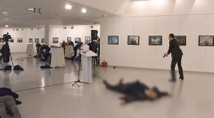 This picture taken on December 19, 2016 shows Andrey Karlov (2ndR), the Russian ambassador to Ankara, lying on the floor after being shot by a gunman (R) during an attack during a public event in Ankara. (STRINGER/AFP/Getty Images)