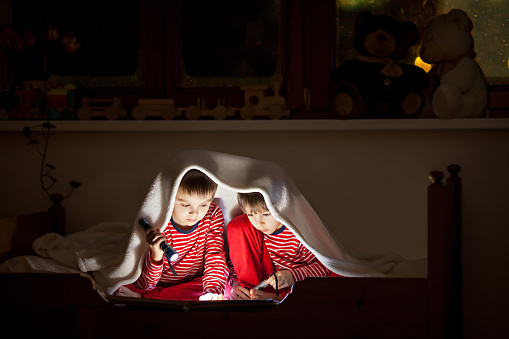 Two sweet boys, reading a book in bed after bedtime