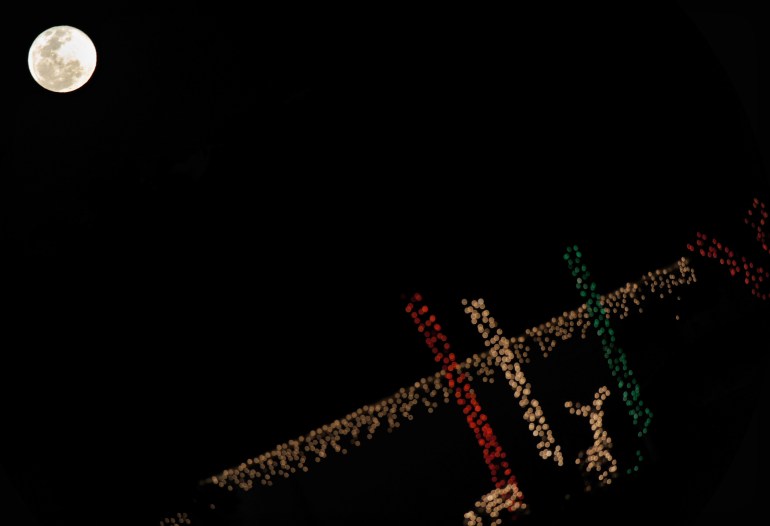 The full moon appears in the sky over Christmas decorations. (Photo credit: Jewel Samad/AFP/Getty Images)