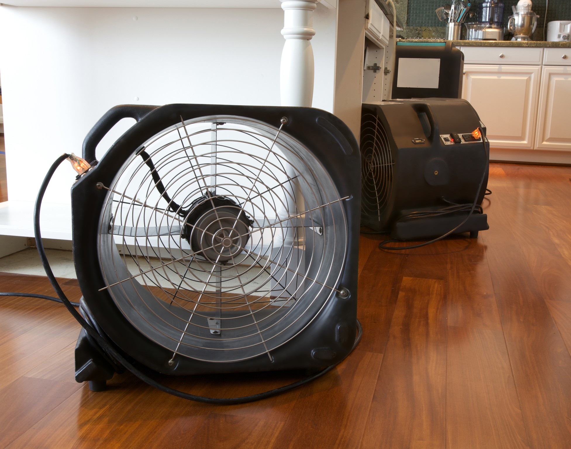 Water damage in kitchen with industrial fans and dehumidifier running to dry out leak damage.