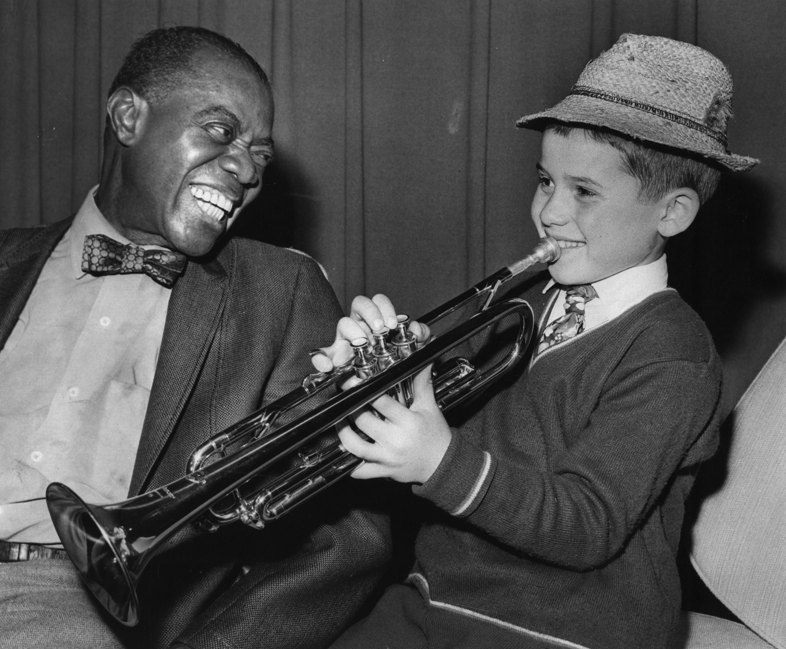 27th October 1970:  Louis 'Satchmo' ('Satchelmouth') Armstrong (1900 - 1971), the great jazz trumpeter and vocalist meets nine year old fan Enrico Tomasso from Leeds, who travelled to London Airport specially to see his idol, and played him a tune on the trumpet.  