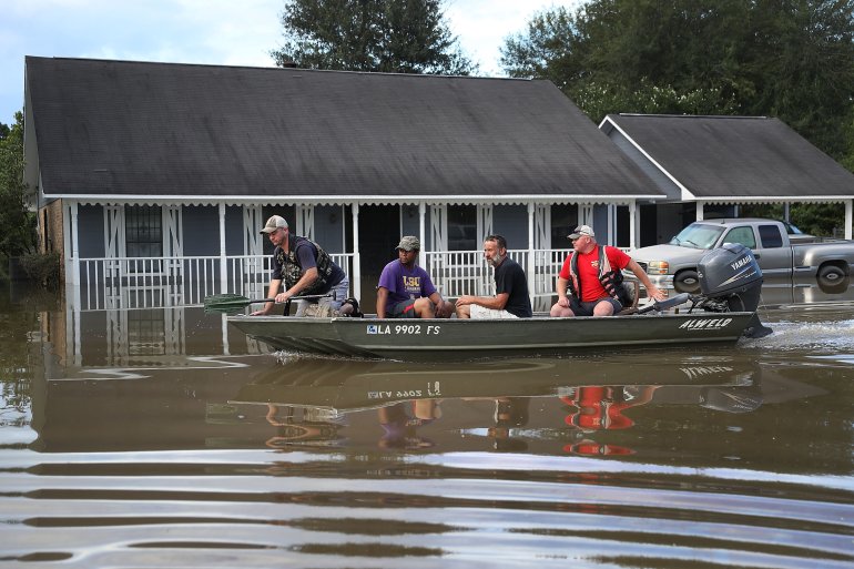 BATON ROUGE, LA - AUGUST 15: Richard Schafer navigates a boat past a flooded home on August 15, 2016 in Baton Rouge, Louisiana. Record-breaking rains pelted Louisiana over the weekend leaving the city with historic levels of flooding that have caused at least seven deaths and damaged thousands of homes. (Photo by Joe Raedle/Getty Images)