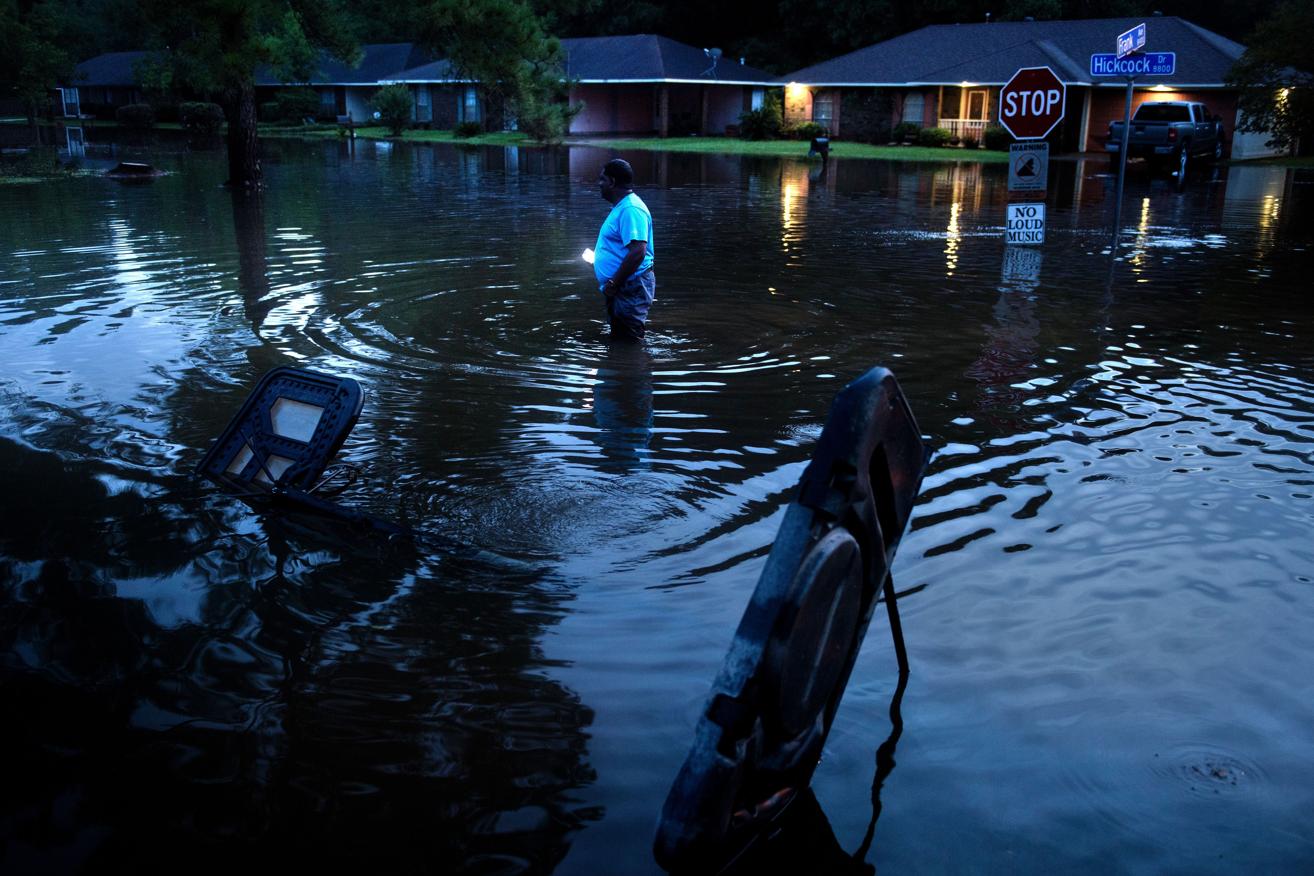 TOPSHOT - Tracy Thornton walks to his house through a flooded neighborhood August 15, 2016 in Baton Rouge, Louisiana. Floods ravaged the US state of Louisiana, leaving six people dead and thousands more forced to flee rising waters after days of catastrophic rainstorms.   / AFP / Brendan Smialowski        (Photo credit should read BRENDAN SMIALOWSKI/AFP/Getty Images)