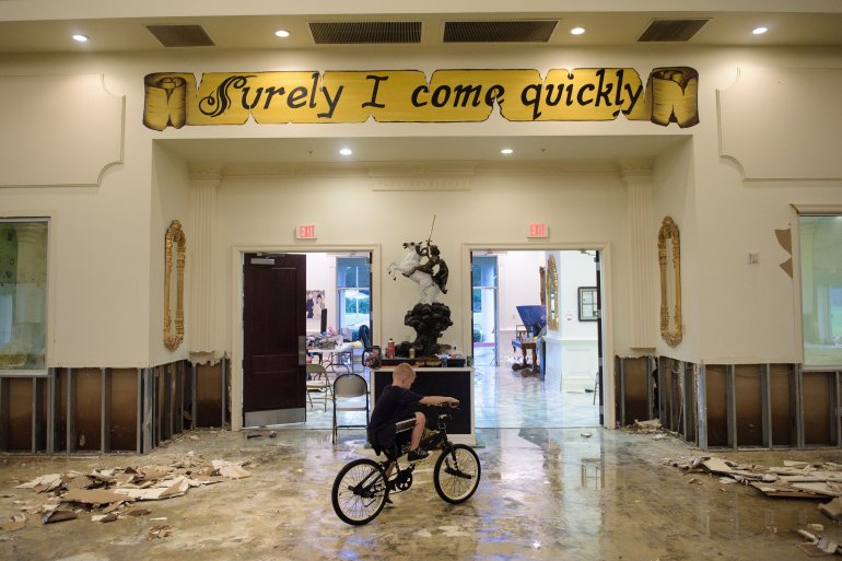 A boy rides his bike inside the flood damaged Life Tabernacle Church on August 15, 2016 in Baton Rouge, Louisiana. Floods ravaged the US state of Louisiana, leaving six people dead and thousands more forced to flee rising waters after days of catastrophic rainstorms. / AFP / Brendan Smialowski (Photo credit should read BRENDAN SMIALOWSKI/AFP/Getty Images)
