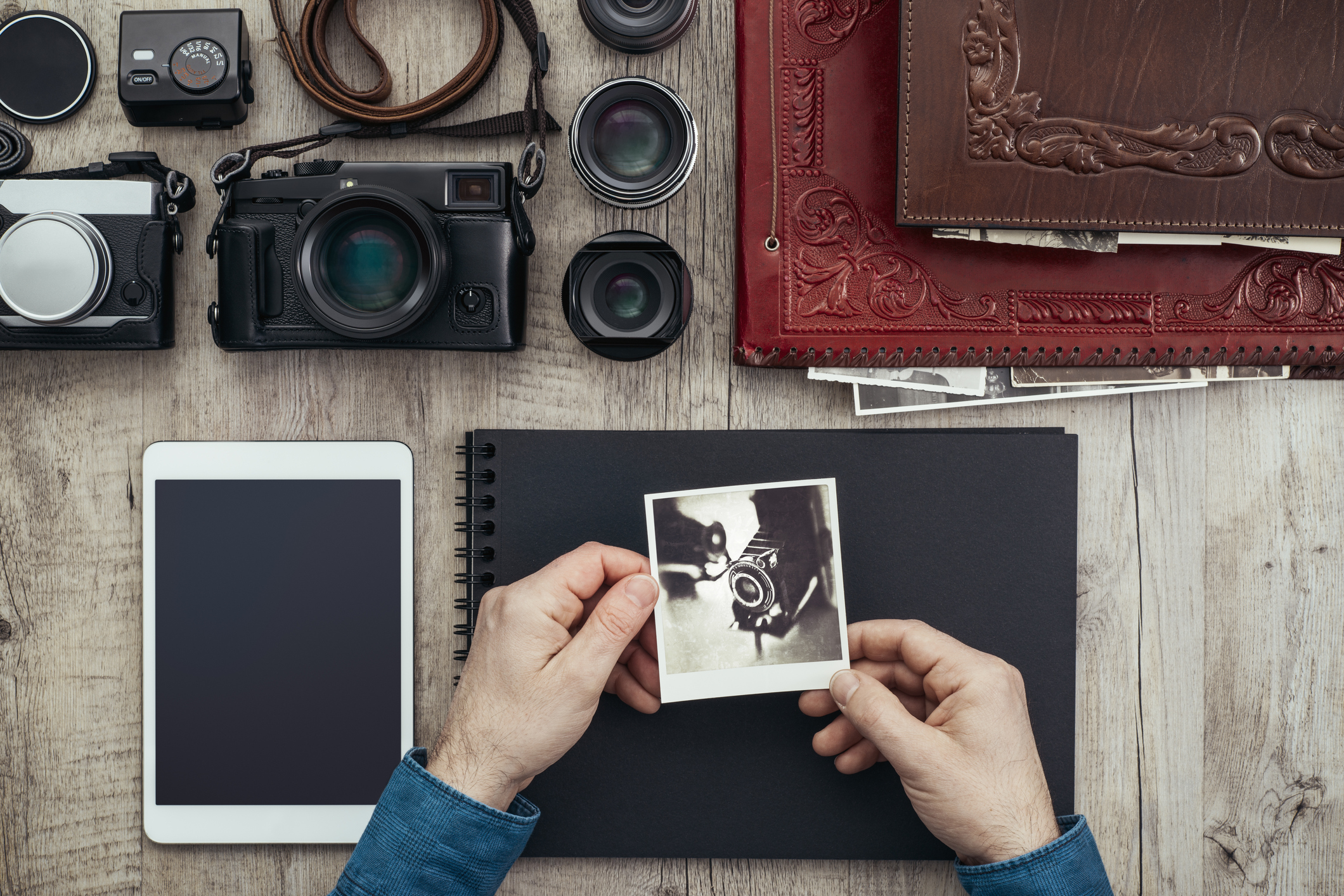 Photographic equipment, digital cameras and tablet on a vintage desktop, a photographer is creating his photo album