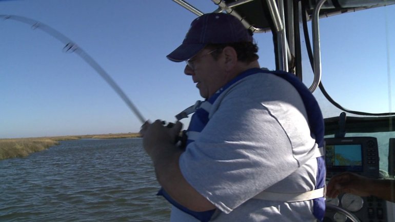 Spud landing a redfish on LBJ's boat (WGNO-TV)