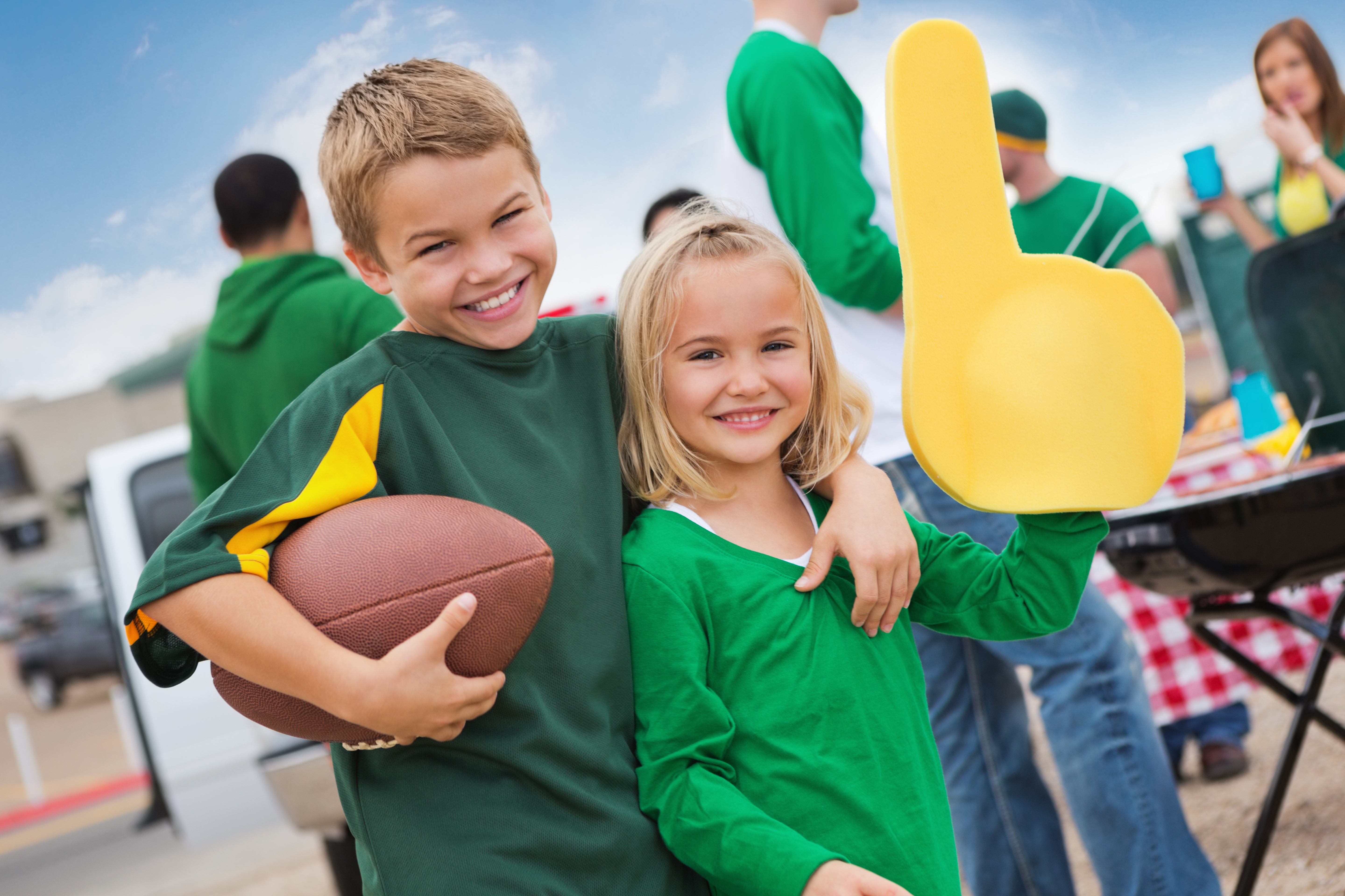 Kids cheering sports team during college football stadium tailgate party.