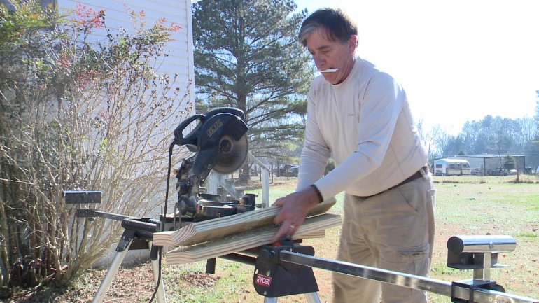 A CASA volunteer saws lumber for a wheelchair ramp.