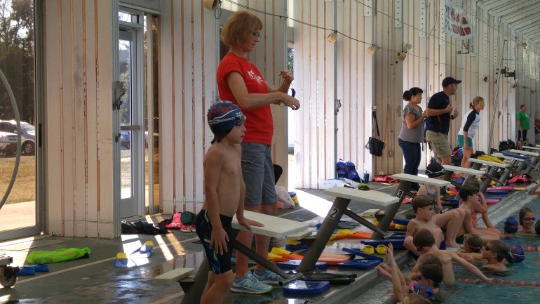 Jan Bunch with a young swimmer near a starting block.