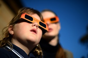 A child watches a partial solar eclipse with a woman at the Sydney Observatory on May 10, 2013. (Credit: SAEED KHAN/AFP/Getty Images)