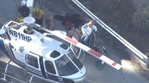 Two people injured in the crash of a small plane in Big Bear hold hands while first responders treat a third victim near Big Bear on Oct. 16, 2014. (Credit: KTLA)