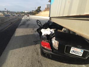 A sedan appeared crushed under a big rig trailer after a crash on the 110 Freeway in San Pedro on Oct. 14, 2014. (Credit: KTLA)