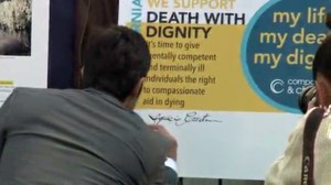 Supporters sign an oversized petition in favor of death with dignity laws in California at a rally in downtown Los Angeles on Oct. 30, 2014. (Credit: KTLA)