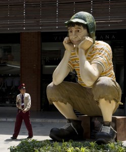 A security guard walks next to a commemorative sculpture of the beloved Spanish-language television character 'El Chavo del Ocho' — played by Mexican actor Roberto Gomez Bolaños — exhibited at the Mall Chipichape in Cali, Colombia. (Credit: Luis Robayo/AFP/Getty Images)