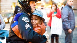 In a photo shared over 150,000 times on Facebook, 12-year-old Devonte Hart, who was previously holding a sign stating "Free Hugs," is seen embracing Portland, Oregon, police Sgt. Bret Barnum on Nov. 25, 2014. (Credit: Johnny Nguyen/ http://www.chambersvisuals.com )