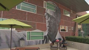 A student sits in front of a mural of Joseph Gatto at LACHSA, where Gatto taught for many years. (Credit: KTLA)