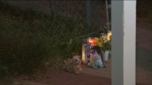 Candles and stuffed animals were left outside the home where two children died in a fire in San Bernardino on Nov. 20, 2014. (Credit: KTLA)