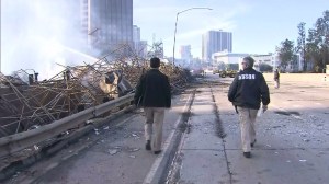 Investigators walk alongside the smoldering ruins of a building that burned in downtown L.A. on Dec. 8, 2014. (Credit: KTLA)