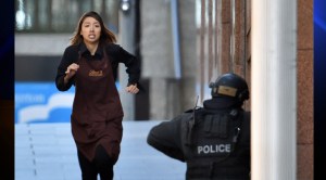 One of the hostages runs toward police from a cafe in the central business district of Sydney on Monday, Dec. 15, 2014. Five people ran out of a Sydney cafe where a gunman has taken hostages and displayed an Islamic flag against the window, witnesses and police said.(Credit: Saeed Khan/AFP/Getty Images)