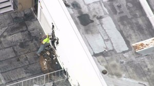 A workers stands by the site where firefighters appeared to have broken down a wall on the roof of Southern California Hospital, which experienced a fire on Jan. 29, 2015. (Credit: KTLA)