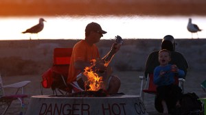 Dave Osinga and his son Zachary sit by a fire ring as the sun sets at Corona del Mar State Beach. (Credit: Robert Gauthier / Los Angeles Times) 