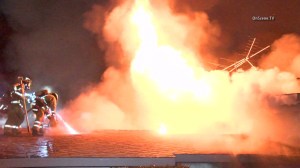 Firefighters are seen on the roof of a house in Garden Grove, where a 3-alarm blaze broke out on Thursday, Feb. 12, 2015. (Credit: OnScene)