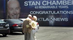 Stan Chambers kisses his wife, Gege, as they walk past a giant banner commemorating his career. He retired in 2010. (Credit: Bob Chamberlin / Los Angeles Times)