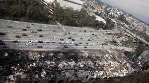 Traffic flows along the 110 Freeway in downtown Los Angeles next to the remains of a portion of the Da Vinci apartment complex that was destroyed by fire in December. (Credit: Barbara Davidson / Los Angeles Times)