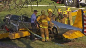 Los Angeles firefighters are seen near a plane that was piloted by Harrison Ford when it crashed at a golf course in Venice on Thursday, March 6, 2015. (Credit: KTLA)