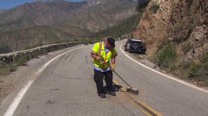 A highway worker cleans up after a skateboarder was killed on Glendora Mountain Road on March 20, 2015. (Credit: KTLA)