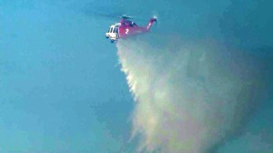 A firefighting helicopter works above a blaze in Santa Clarita on March 23, 2015. (Credit: KTLA)