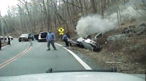 Police officers pulled a woman from an overturned car before it burst into flames on Thursday, April 16, 2015. (Credit: Kinnelon Police Department)