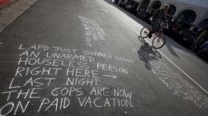 A man on a bike pedals past a messages written in chalk near the site of a May 5, 2015, fatal LAPD officer-involved shooting of a homeless man in Venice. (Credit: Irfan Khan / Los Angeles Times)