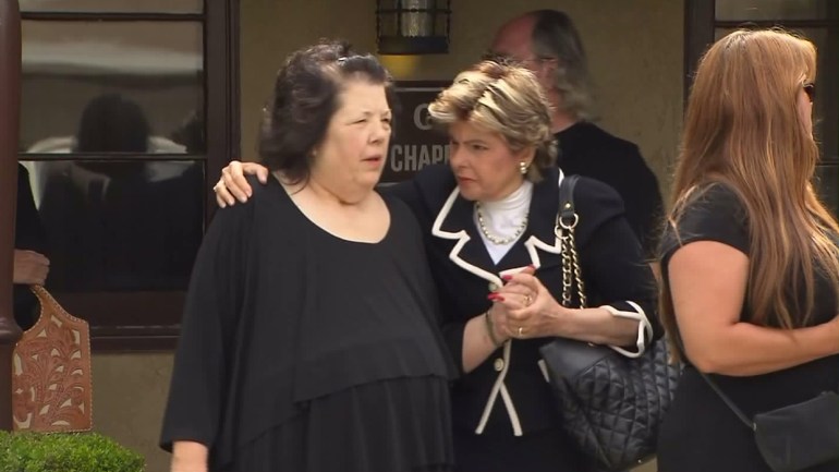 Dianna Bedwell is comforted by Gloria Allred outside a Fontana funeral home after a service for her husband on July 10, 2015. (Credit: KTLA)