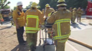 Firefighters rush one of their own away from the scene of a blaze that burned a Glassell Park church on July 7, 2015. Two firefighters were injured. (Credit: KTLA)