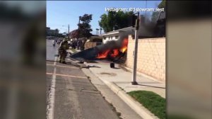 A screenshot from an Instagram video shows firefighters dousing flames with water after a small plane crashed in Riverside on Sunday, July 26, 2015.