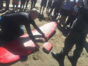 The surfboard Los Osos resident Elinor Dempsey was on when a shark bit a chunk out of it. Surfer Jay Thompson measures the bite mark. (Credit: Patrick S. Pemberton/The San Luis Obispo Tribune)